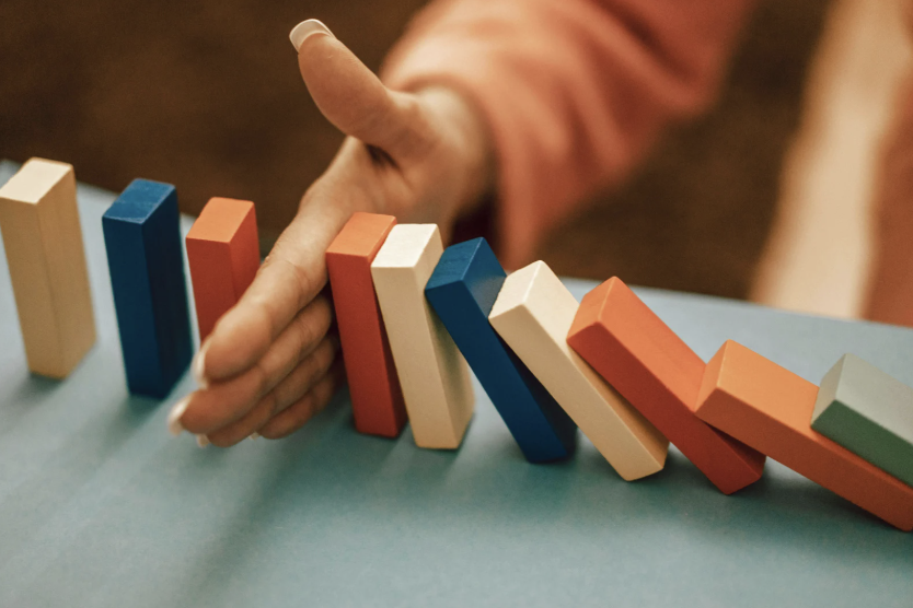 hand stopping a line of blocks from falling like dominoes